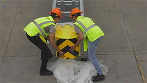 Two workers in reflective personal protective equipment, and hardhats, attaching the Delta TL-2+ Nose Module with 4 bolts.