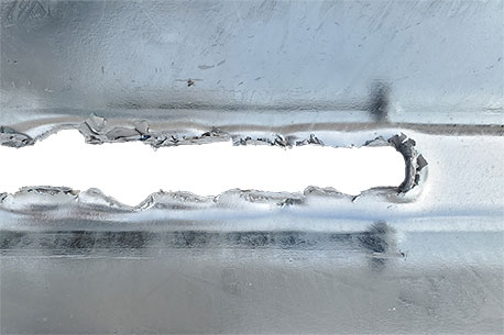A close up image detailing the tear bolts shearing through the Delta TL-2+ Thrie-Beam Panels