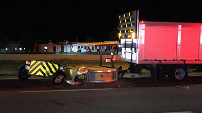 A damaged Scorpion Towable Attenuator attached to a work truck with a lighted arrowboard warning sign.