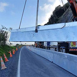 The HV2 Barrier being hoisted off a flatbed truck and onto the road surface.