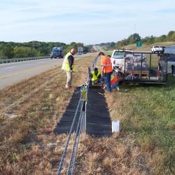 TrafFix Weed Mats being installed along a highway.